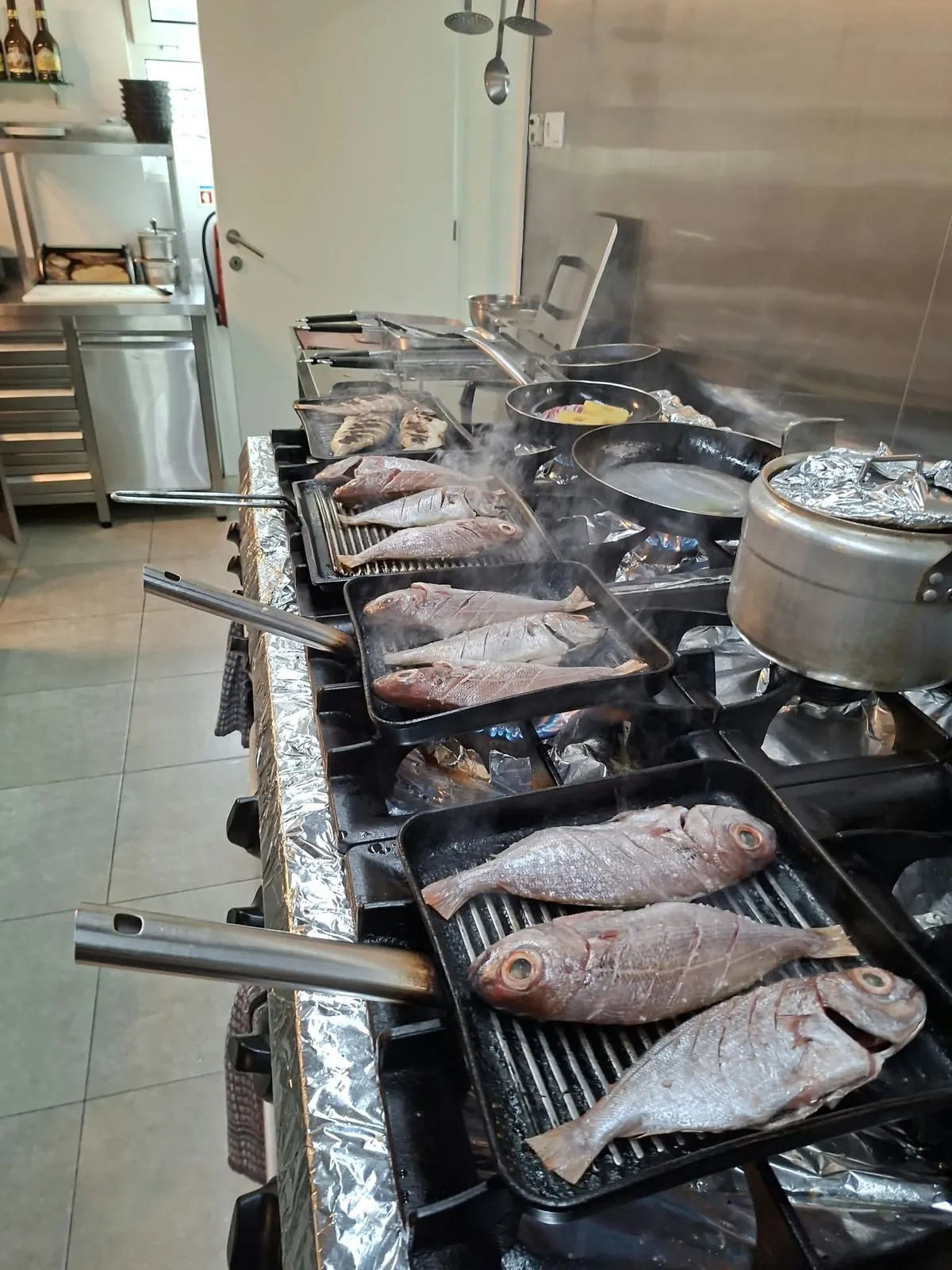 Peixes inteiros a grelhar na cozinha do restaurante
