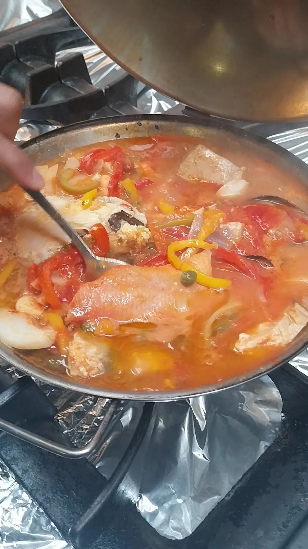 Cataplana aberta, ainda a ferver, com peixe, tomate e pimento